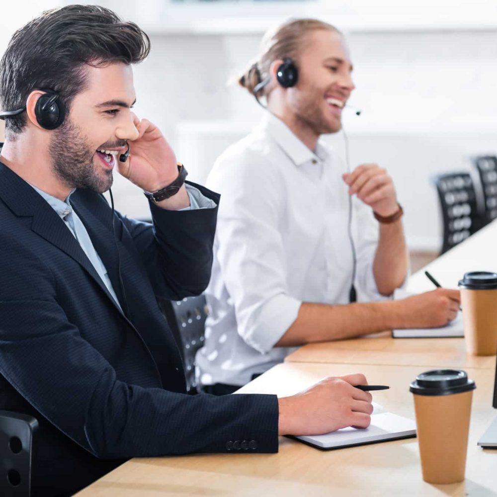 side-view-of-male-call-center-operators-in-headsets-at-workplace-in-office.jpg